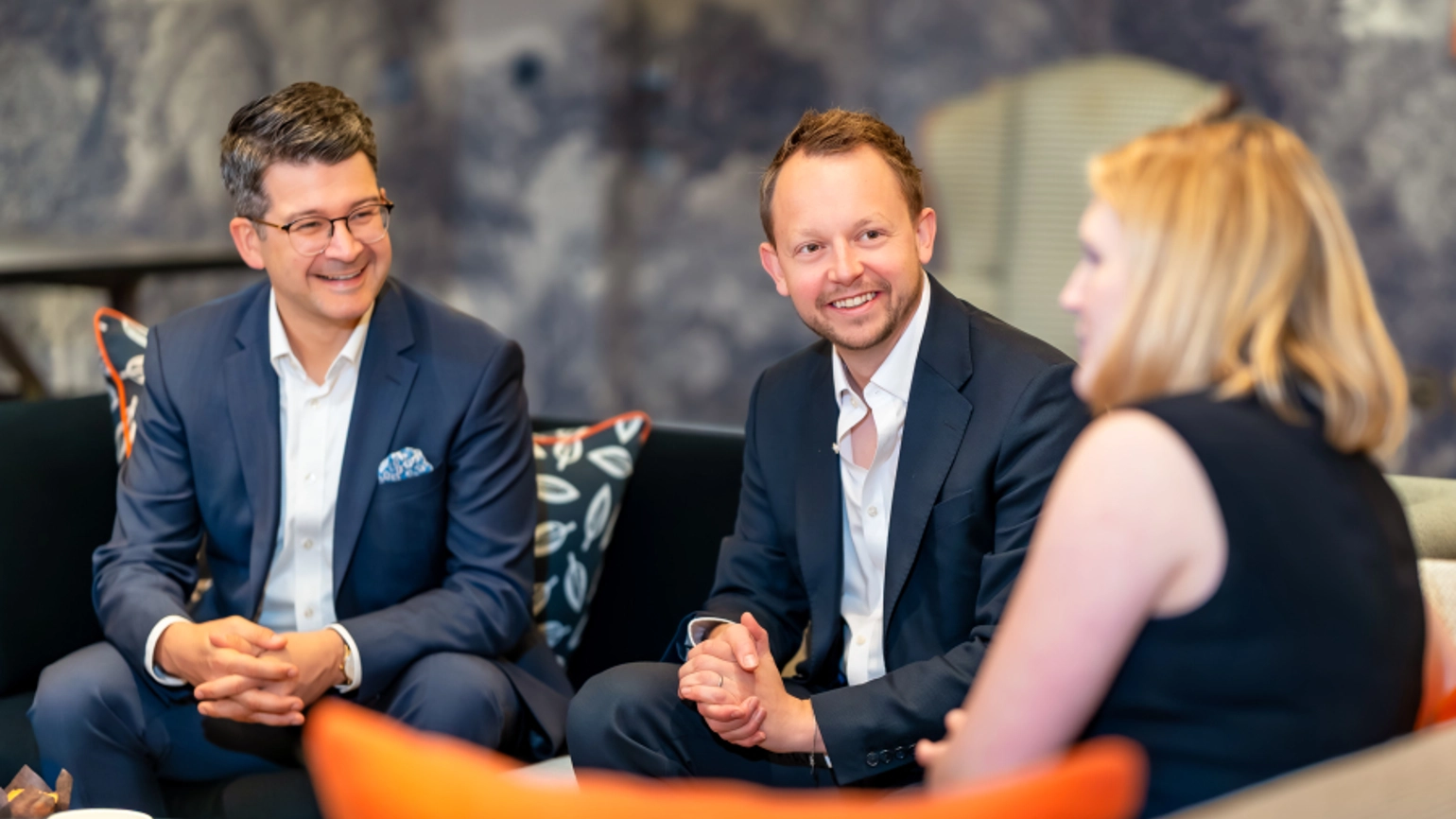 2 men and 1 woman sat talking on orange sofa 2 men and 1 woman sat talking on orange sofa