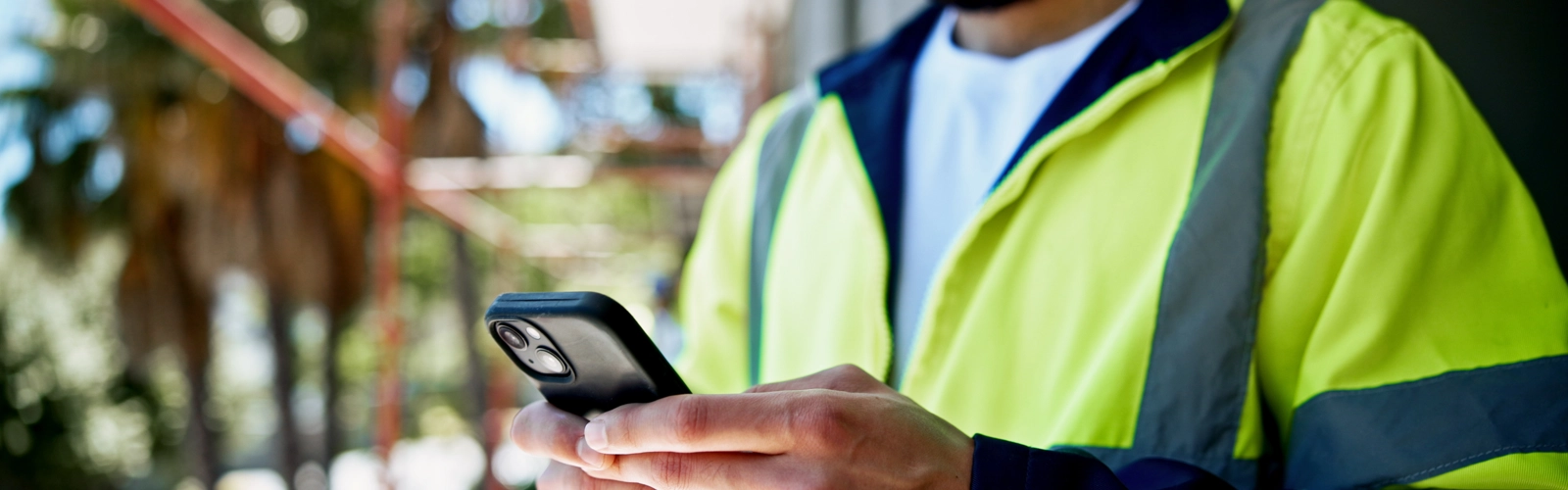 Man in high-vi vest looking at his phone Man in high-vi vest looking at his phone