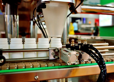 Machinery putting supplements into plastic white bottles Machinery putting supplements into plastic white bottles