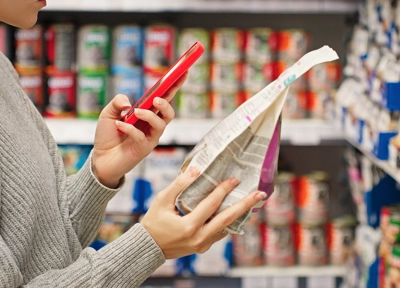 Person scanning food label with phone in grocery store aisle Person scanning food label with phone in grocery store aisle