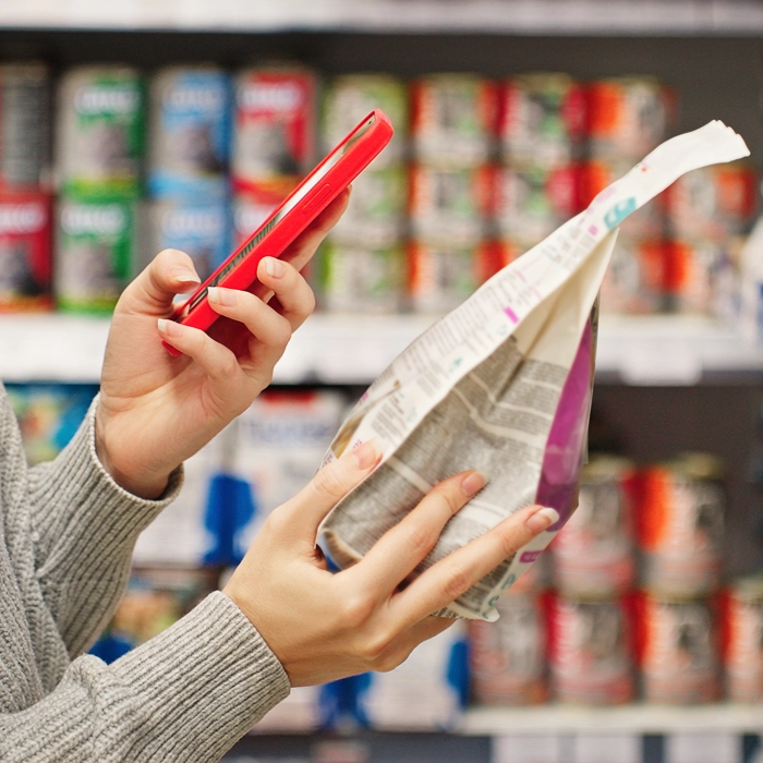 Person scanning food label with phone in grocery store aisle Person scanning food label with phone in grocery store aisle
