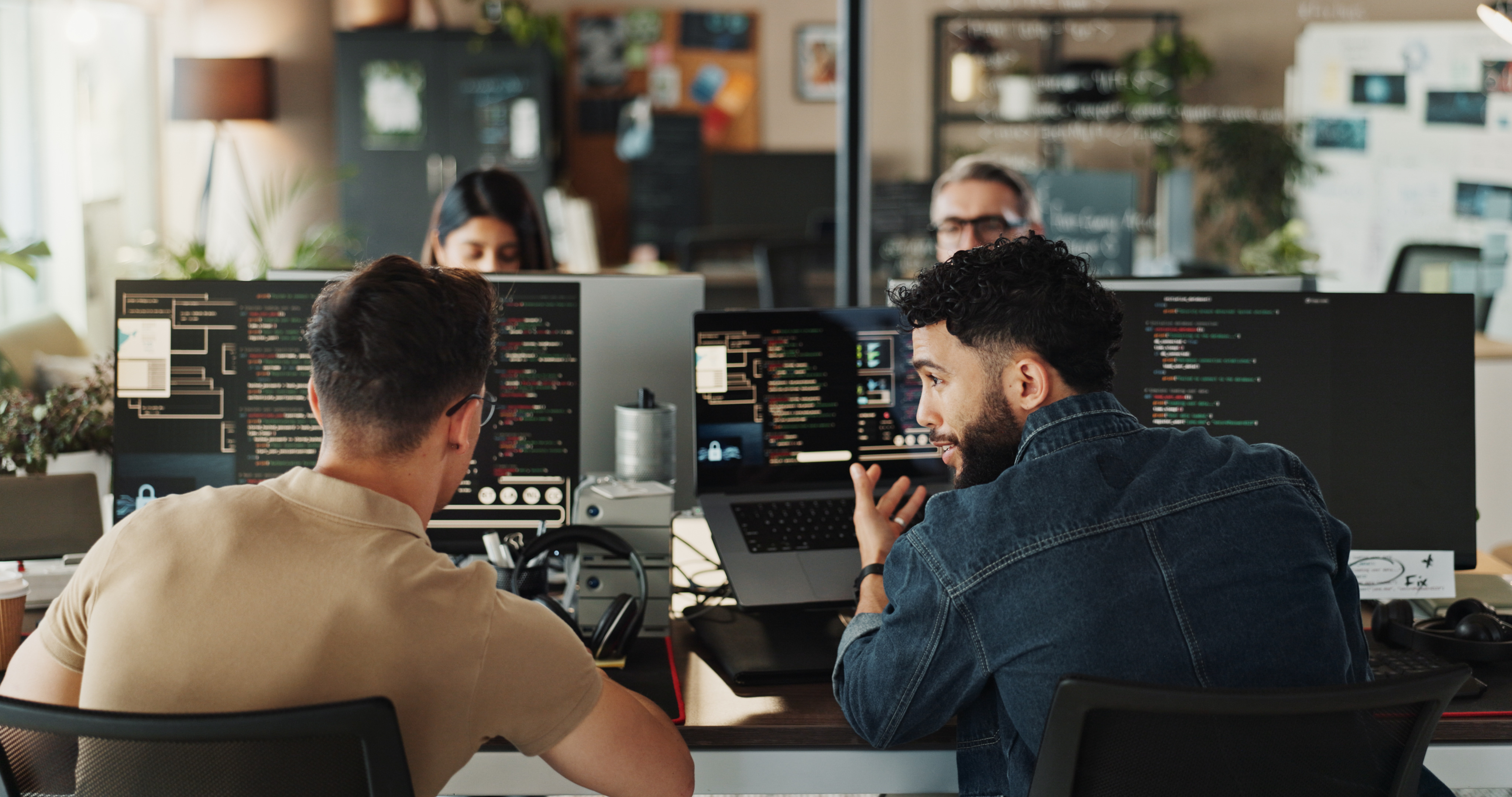 Two men sitting in front of computers creating software