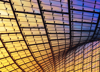 Curved glass and steel ceiling structure glowing with warm yellow and cool purple light. Curved glass and steel ceiling structure glowing with warm yellow and cool purple light.