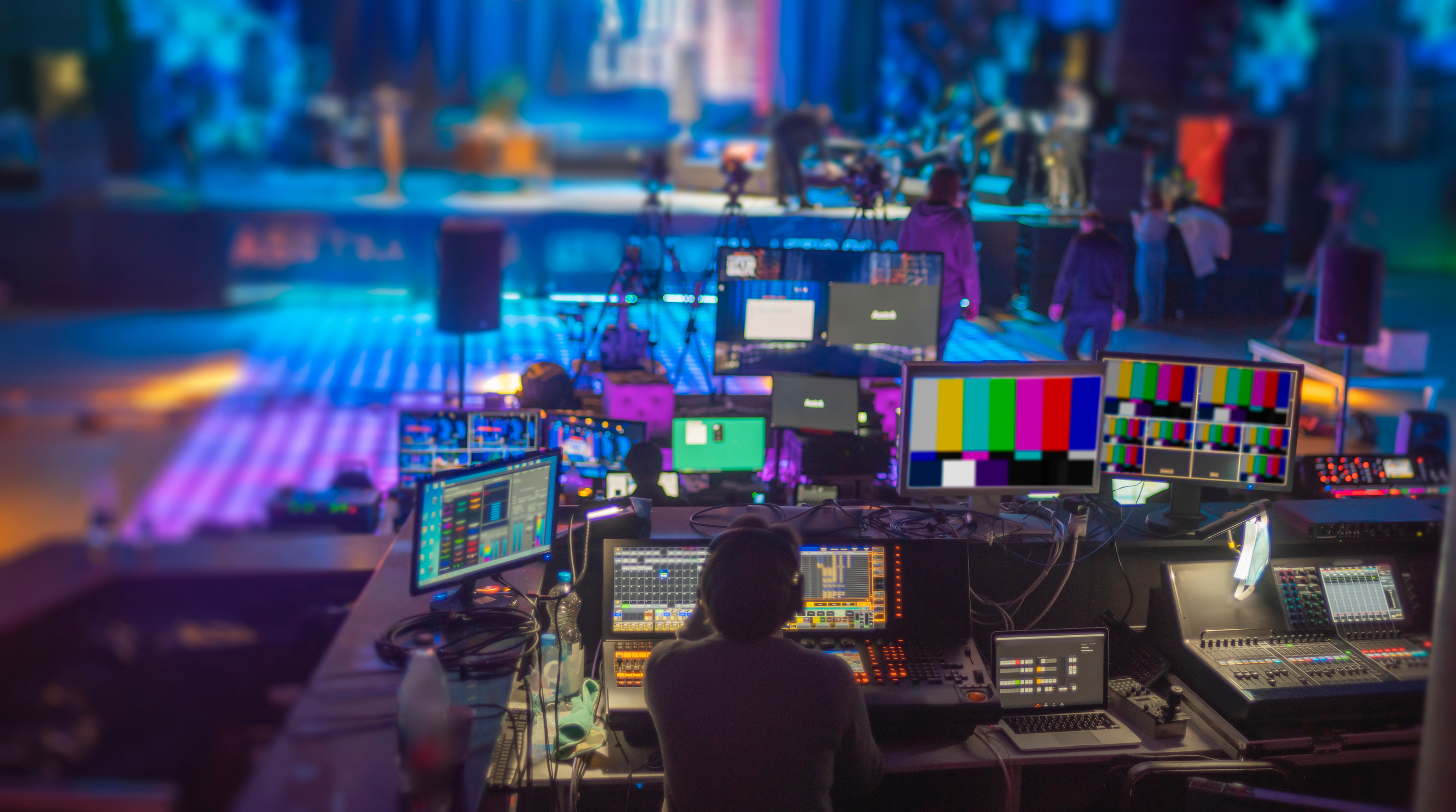 Person sitting behind video editing screens in live tv media studio
